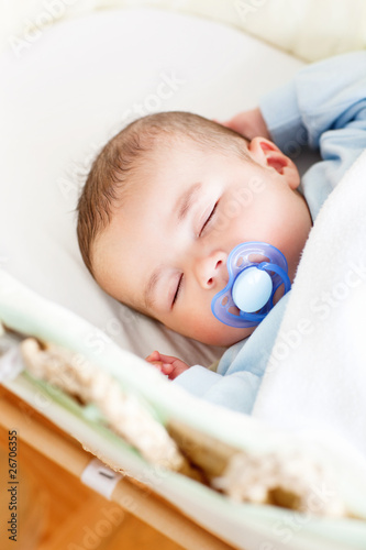 Portrait of a sleeping baby lying in his cradle with his dummy photo