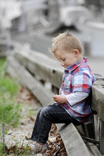Little boy sitting on a wooden wall