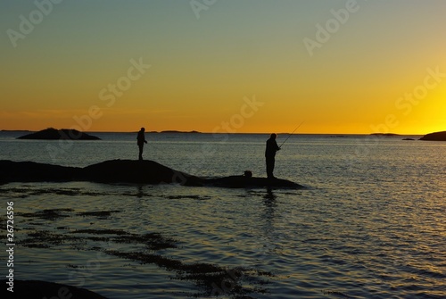 Fisherman silhouettes against sunset © VitaminFT