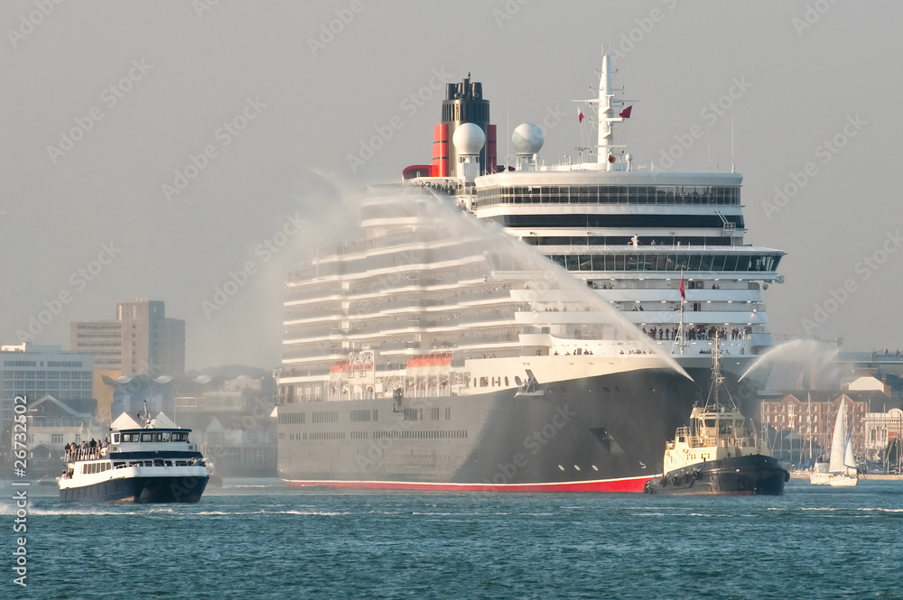 large ocean liner escorted from port by smaller boats