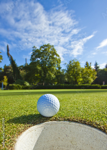 A golf ball just as it drops into the cup on a beautiful day