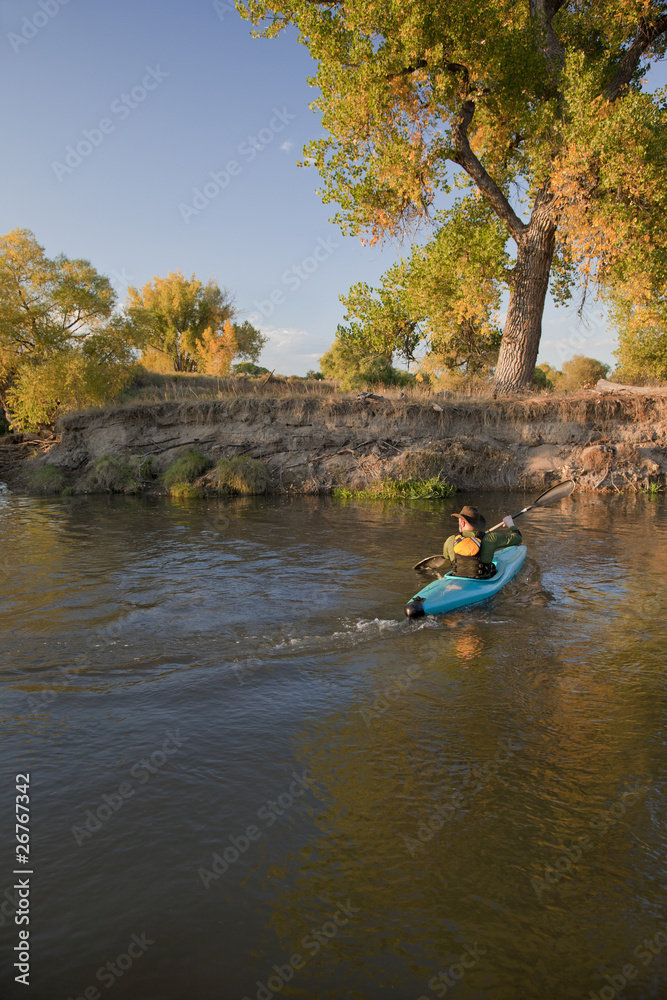 kayaker paddling across a river