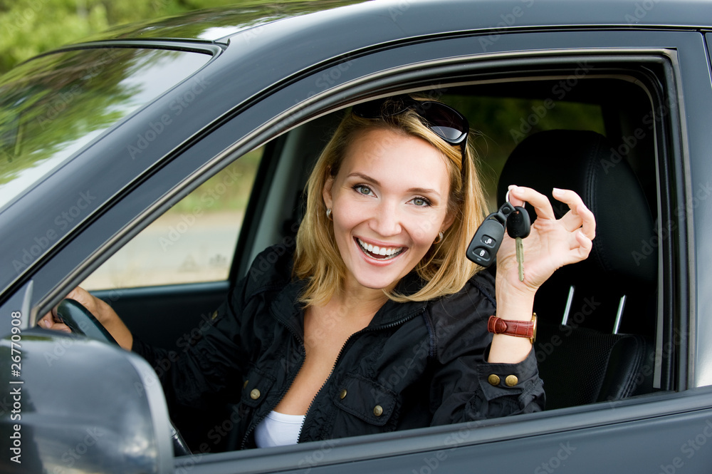 Beautiful young happy woman in the new car with keys - outdoors