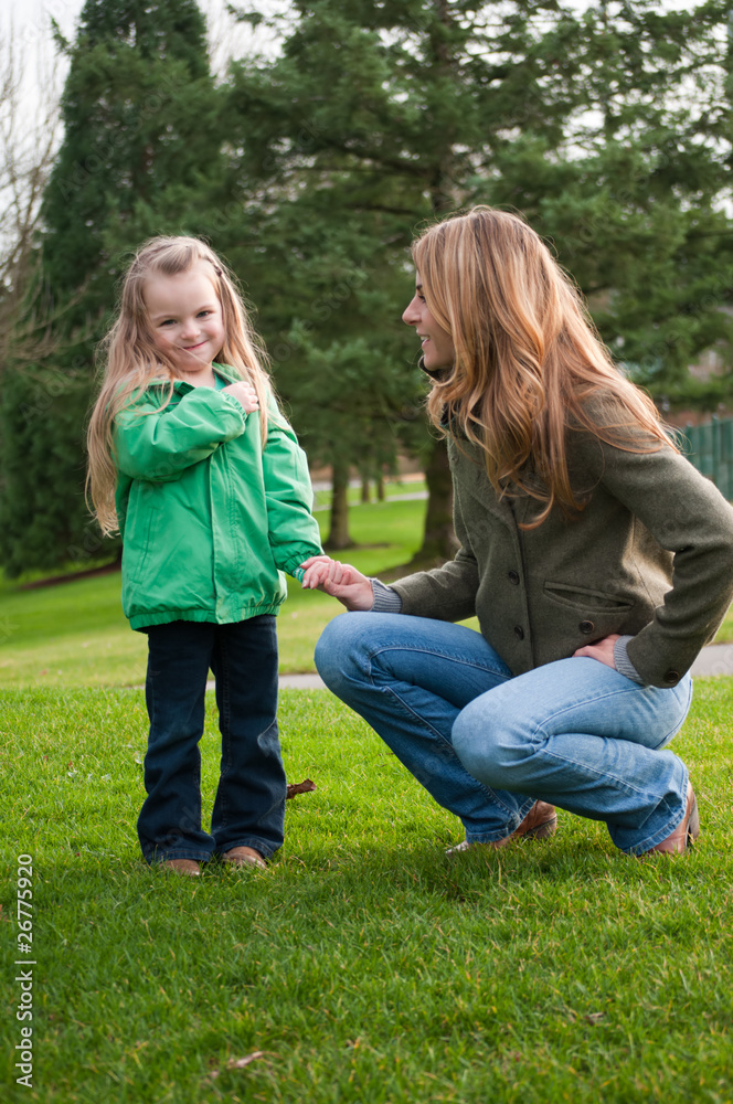 Fototapeta premium Smiling girl holding mother's hand at the park