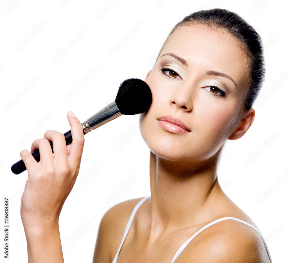 woman applying powder on cheek with brush