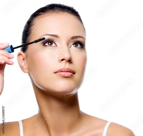 Woman applying mascara on eyelashes