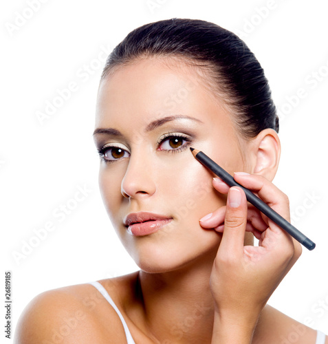 woman applying eyeliner on eyelid with pensil photo