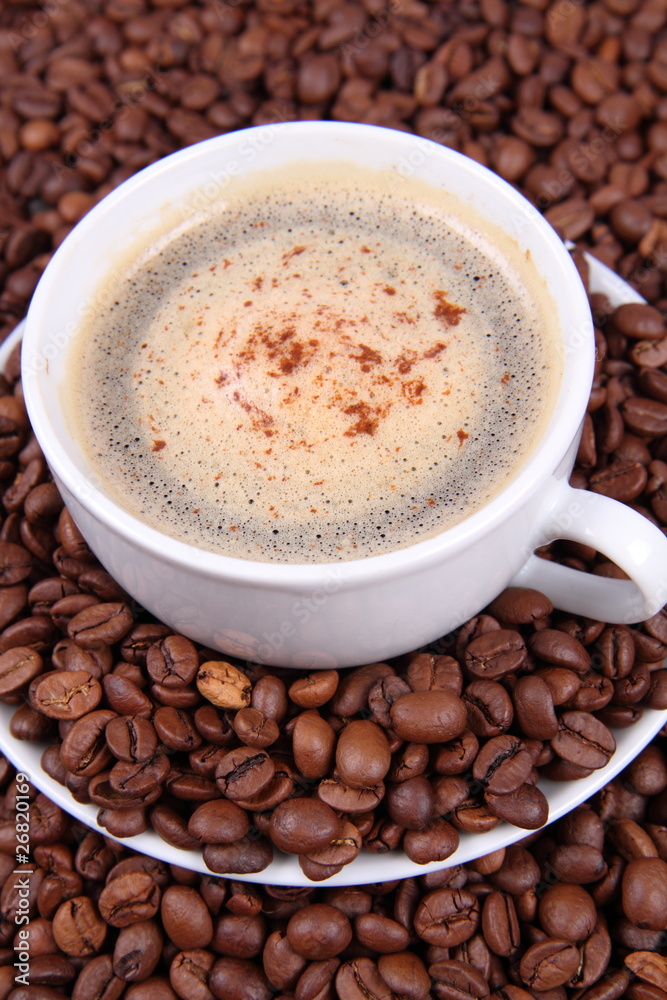 Cup of coffee with cinnamon with coffee beans around it Cup of coffee with cinnamon with coffee beans around it