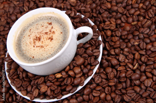 Cup of coffee with cinnamon on coffee beans background