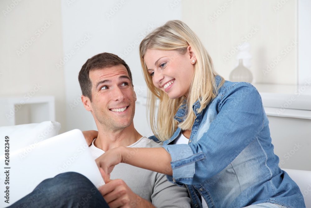 Closeup of couple sitting in sofa surfing on internet Closeup of couple sitting in sofa surfing on internet