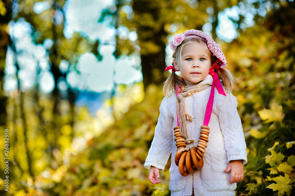 Pretty little girl with bagels in autumn park