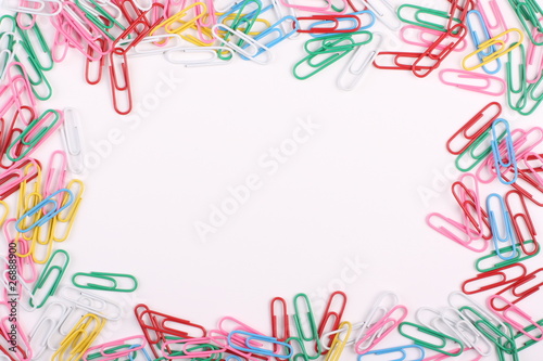 Multi-coloured paperclips form a border on white copy space