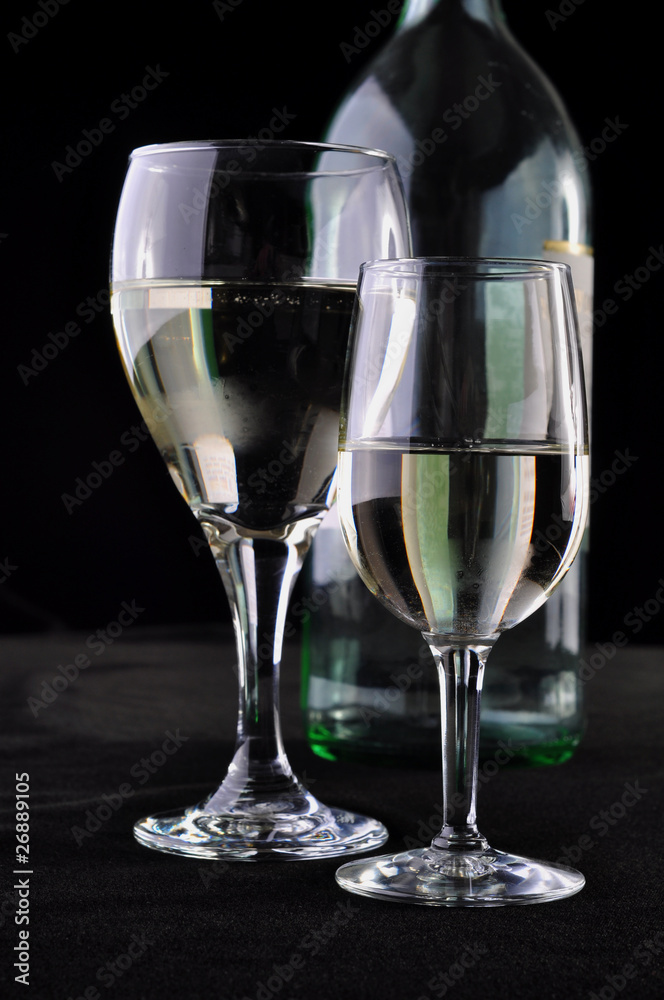Two glasses with white wine in exhibition with an empty bottle Two glasses with white wine in exhibition with an empty bottle