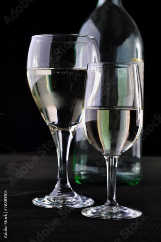 Two glasses with white wine in exhibition with an empty bottle