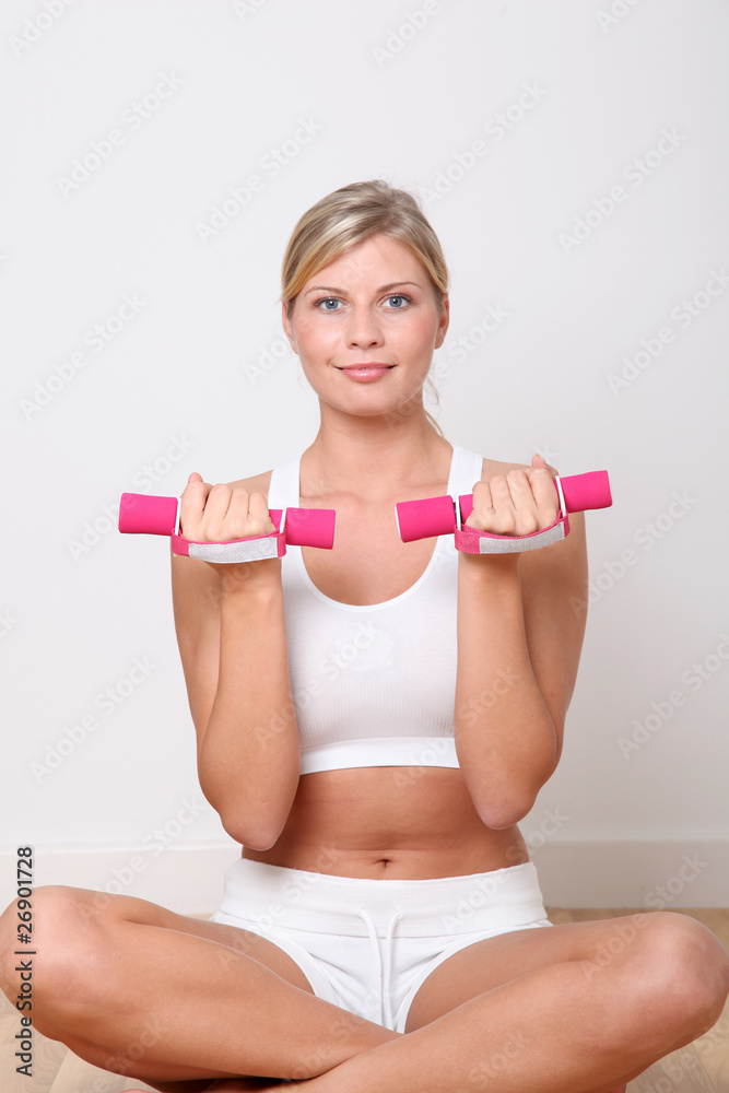 Beautiful blond woman lifting dumbbells in fitness gym Beautiful blond woman lifting dumbbells in fitness gym