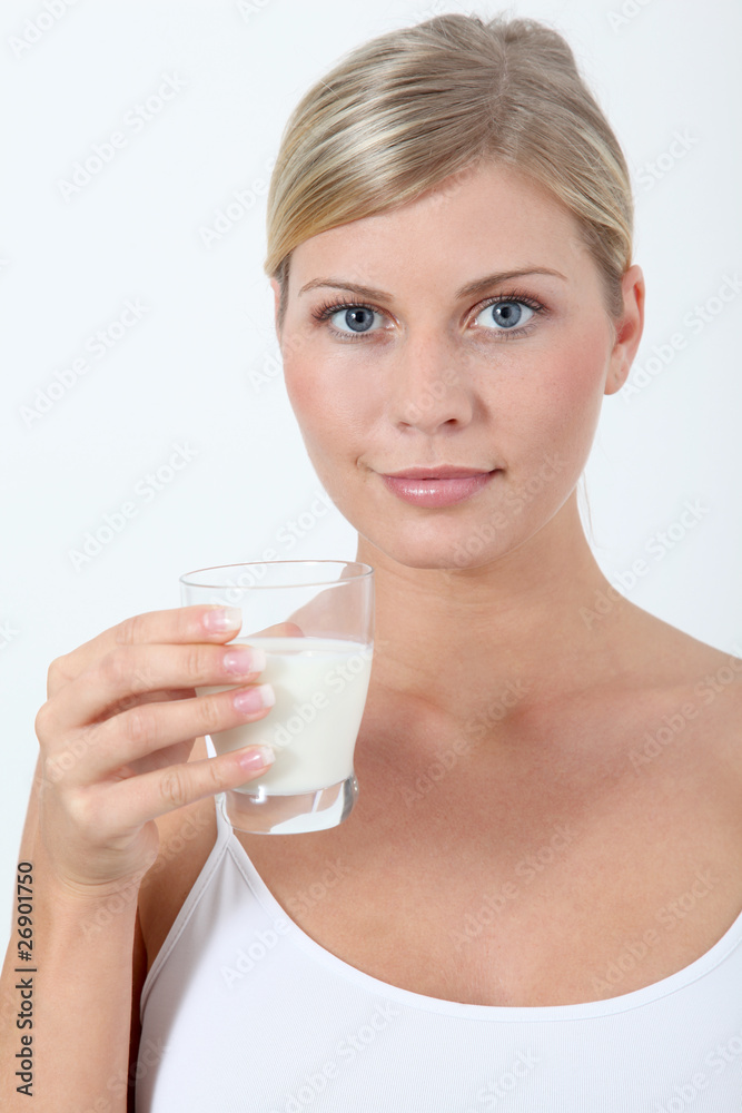 Beautiful blond woman holding glass of milk - obrazy, fototapety, plakaty 