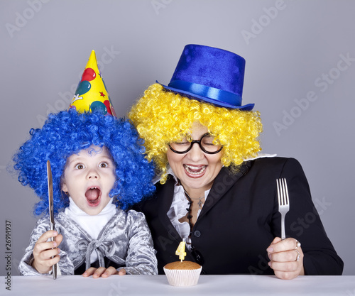 Mother and child in funny wigs and cake at birthday. Studio shot