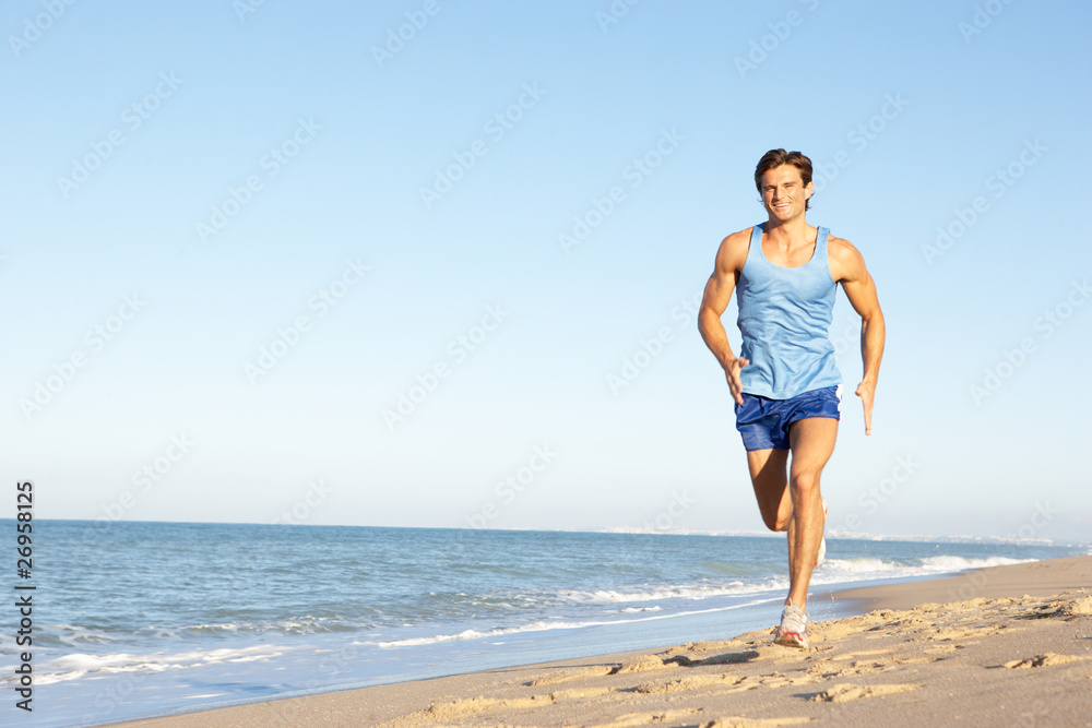 Young Man In Fitness Clothing Running Along Beach Young Man In Fitness Clothing Running Along Beach