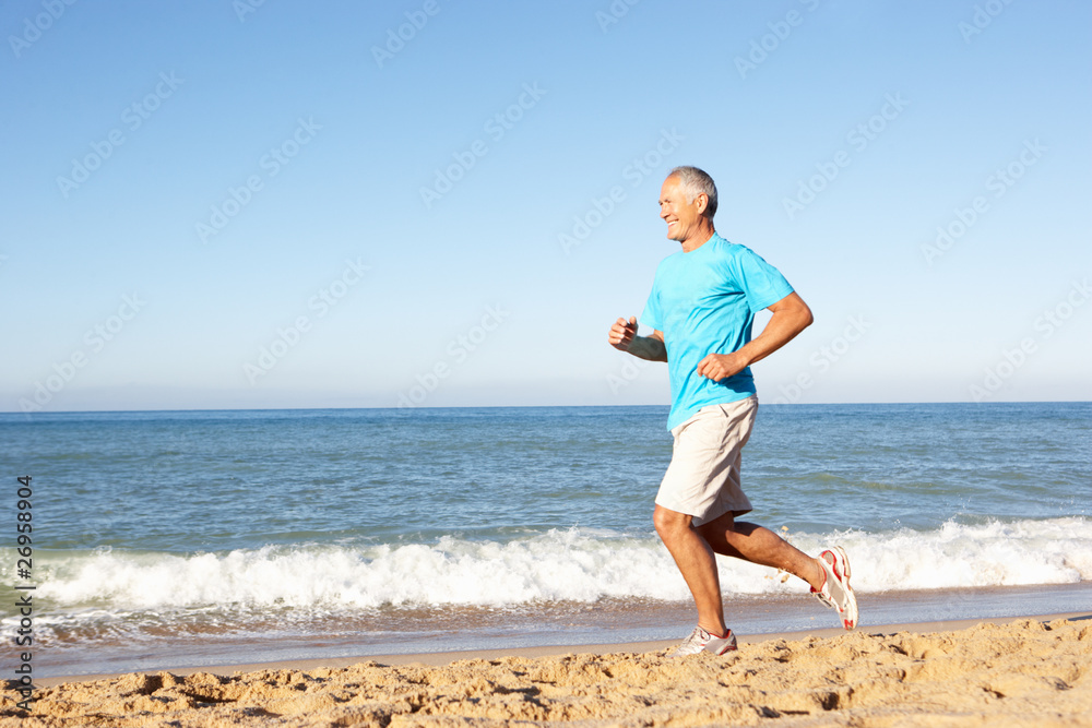 Senior Man In Fitness Clothing Running Along Beach Senior Man In Fitness Clothing Running Along Beach