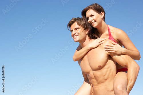 Young Couple Enjoying Piggyback On Beach Holiday