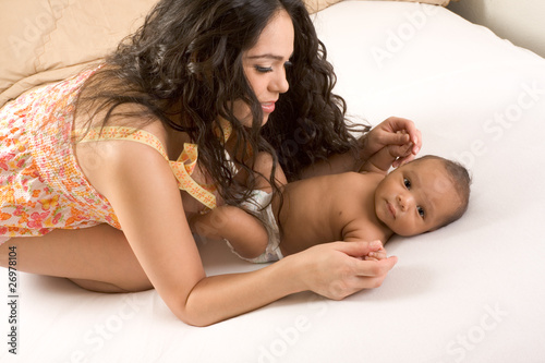 Latina mother playing with her baby boy son on bed
