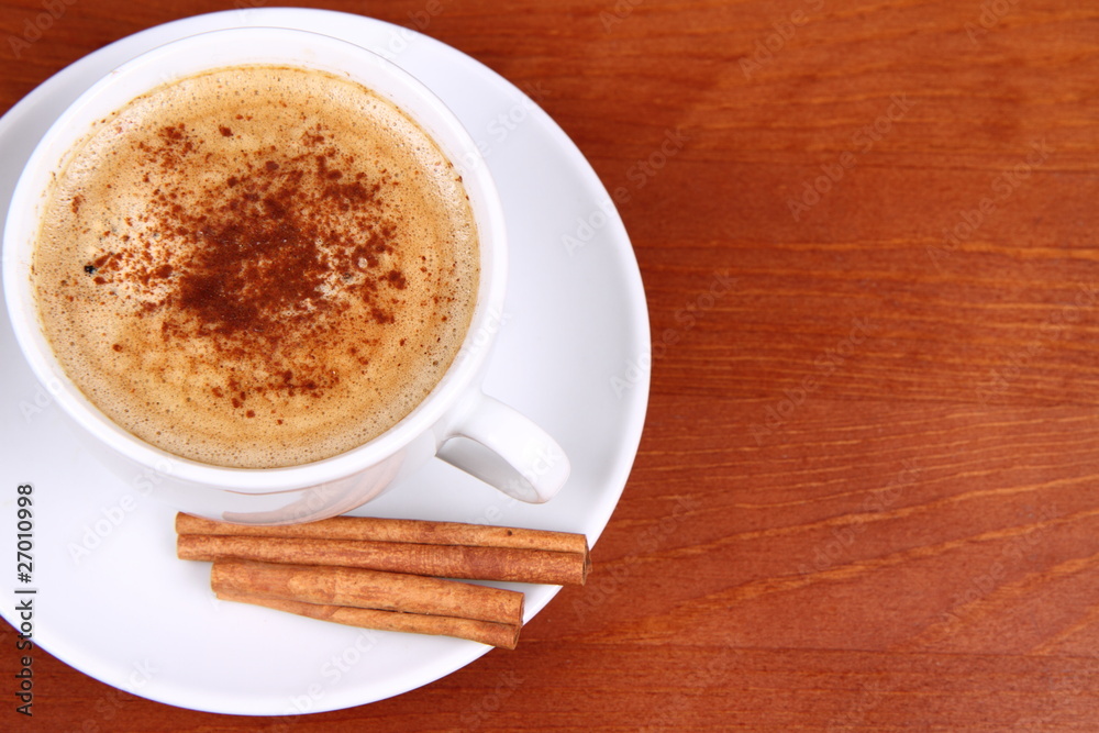 Fototapeta premium Cup of coffee with cinnamon on wooden background