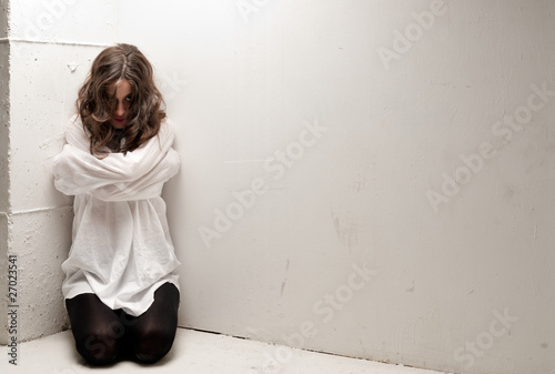 Fotografia Young insane woman with straitjacket on knees looking at camera
