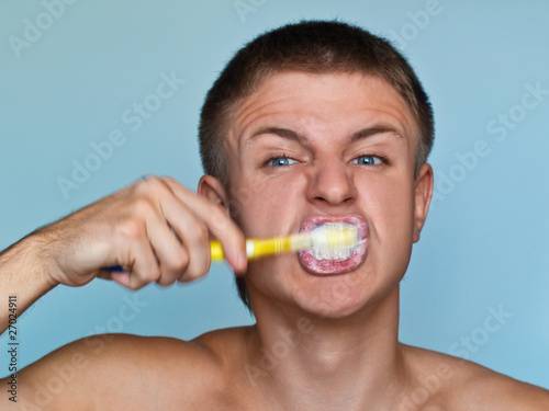a guy brushing his teeth hard