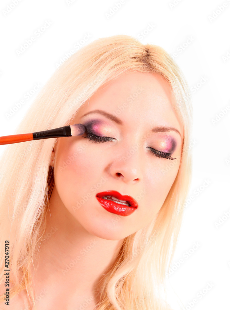 Beautiful young blonde woman with bright make-up and brush on wh Beautiful young blonde woman with bright make-up and brush on wh