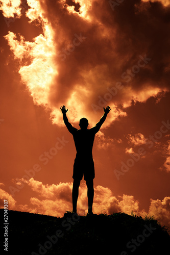 Silhouette of man with arms outstretched to the sky.