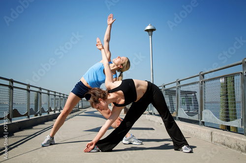 two females stretching on a pier .