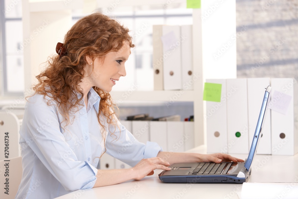Young attractive woman working on laptop in office Young attractive woman working on laptop in office