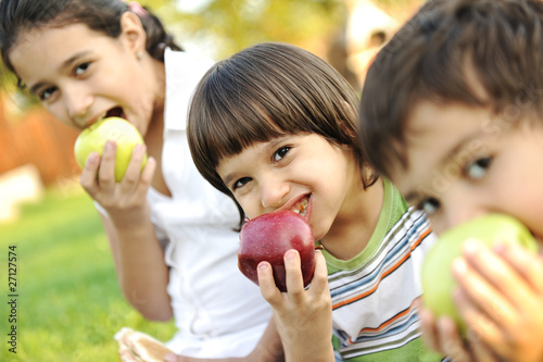 Small group of children eating apples together,