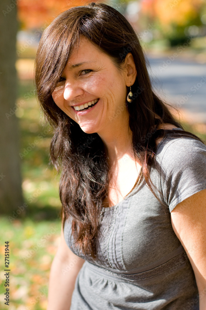 woman in park on autumn day smiling woman in park on autumn day smiling