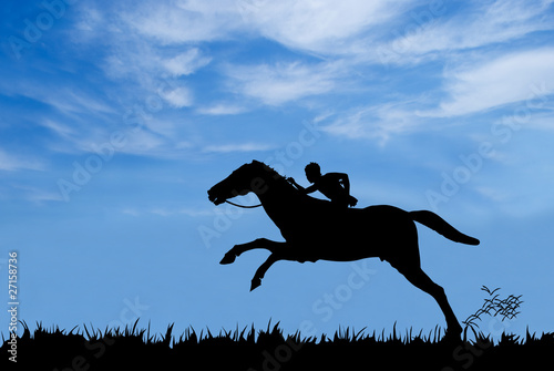 Young boy riding a horse against blue sky