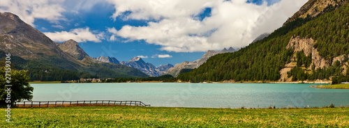 Lakeside view in alpine scenery with blue sky and clouds.