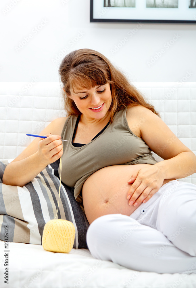 beautiful pregnant woman sitting on sofa and knitting for baby. beautiful pregnant woman sitting on sofa and knitting for baby.