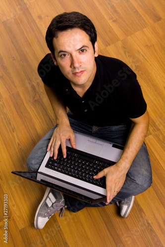 young man sitting on the floor working on laptop computer at hom