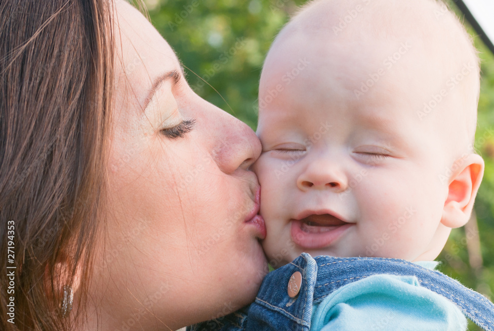 woman tenderly kisses her baby on the cheek woman tenderly kisses her baby on the cheek
