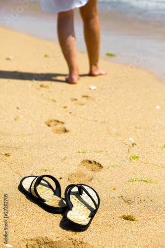 Beach slippers on sand and female feet