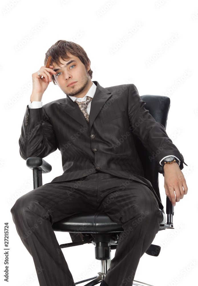 young attractive man with a cigar pensively sitting in an armcha young attractive man with a cigar pensively sitting in an armcha