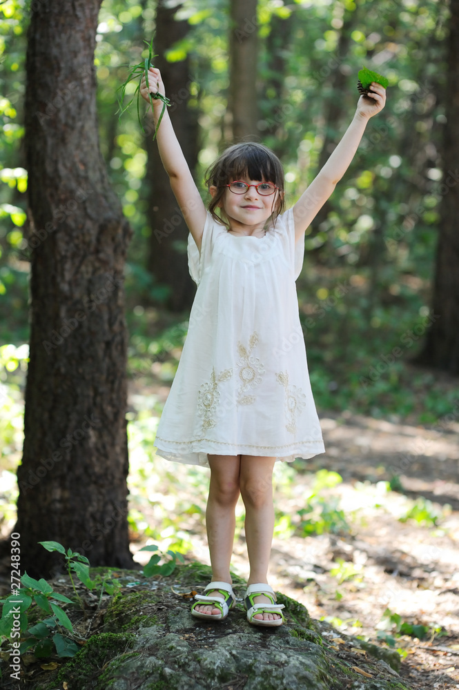 Small girl in glasess and white dress in summer forest