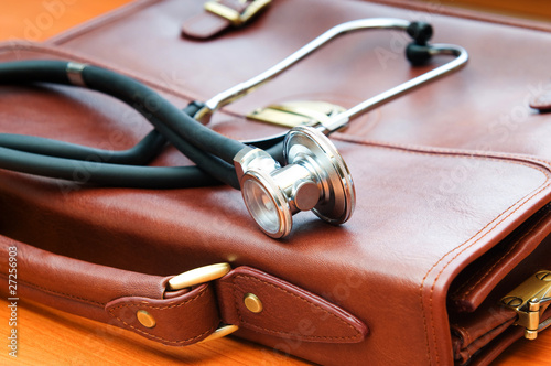 Doctor's case with stethoscope against wooden background photo