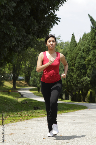 An Asian woman running at a park