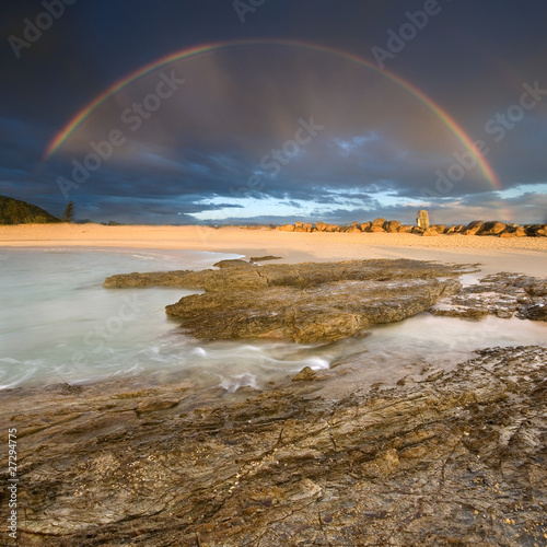 rainbow with rock in foreground at cloudy morning