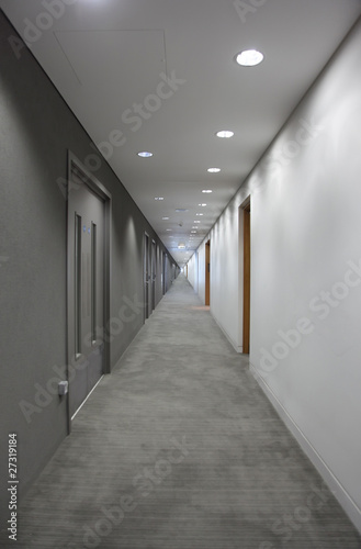 gray hallway with doors. light at the end of the corridor