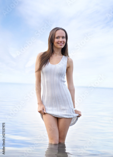 A young and sexy brunette is standing in the water