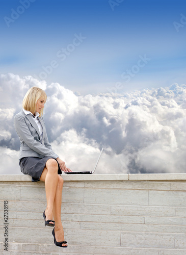 A young blond businesswoman is working outdoors