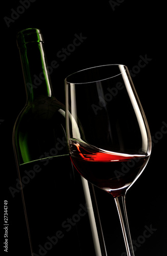 glass of red wine with a bottle and black background