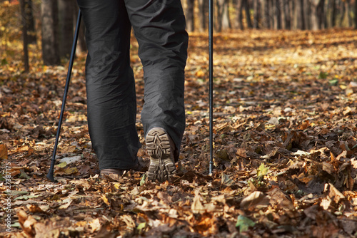 Closeup of shoe sole with Nordic walk sticks in autumn forest